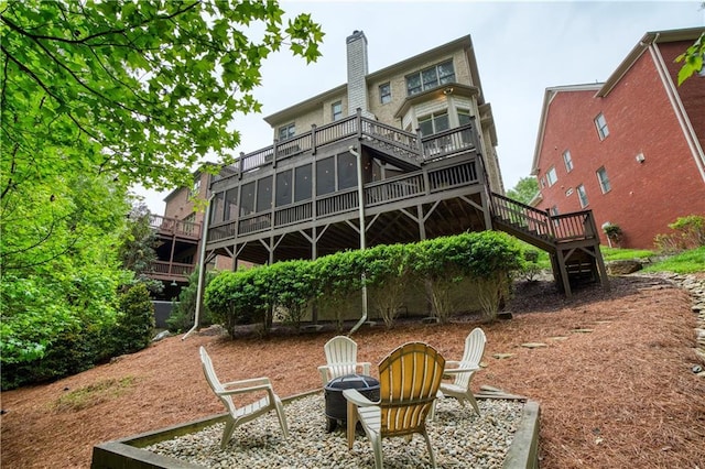 rear view of property featuring stairway, an outdoor fire pit, a wooden deck, and a chimney