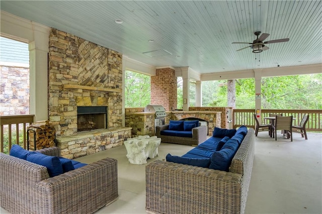 view of patio / terrace with a ceiling fan, an outdoor living space with a fireplace, exterior kitchen, and area for grilling