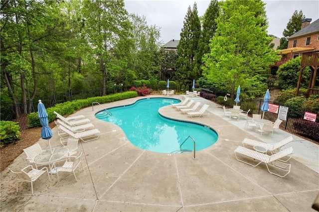 community pool with a patio and fence