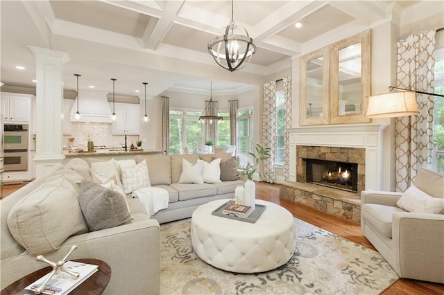 living room with a fireplace, wood finished floors, beamed ceiling, a chandelier, and coffered ceiling