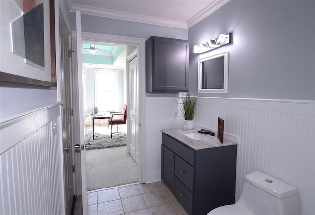 half bathroom with a wainscoted wall, crown molding, toilet, and a skylight