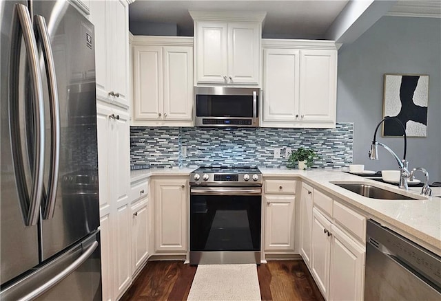kitchen with dark wood finished floors, tasteful backsplash, white cabinets, a sink, and stainless steel appliances