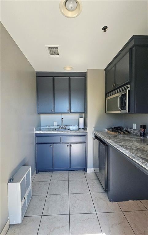 kitchen with stainless steel microwave, light tile patterned floors, visible vents, and baseboards