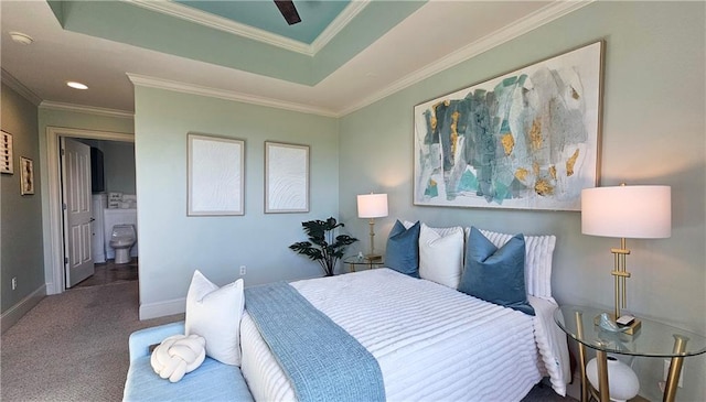 carpeted bedroom with a raised ceiling, baseboards, ornamental molding, and ensuite bath