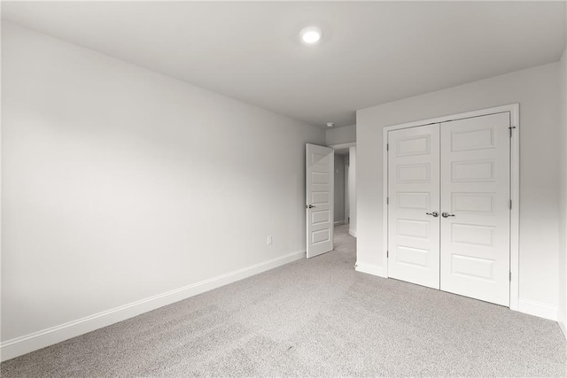 unfurnished bedroom featuring carpet floors, baseboards, and a closet