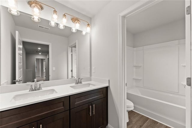 full bathroom with toilet, wood finished floors, a sink, and visible vents