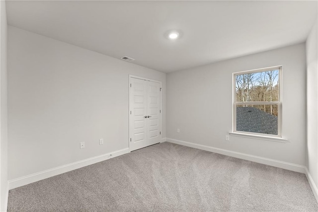 carpeted empty room featuring visible vents and baseboards