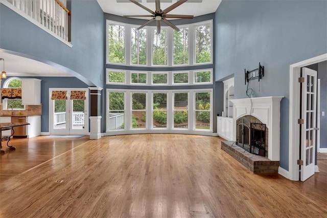 212 Thorncliff Way, Acworth, GA 30101 - unfurnished living room with a high ceiling, ceiling fan, a fireplace, arched walkways, and wood finished floors
