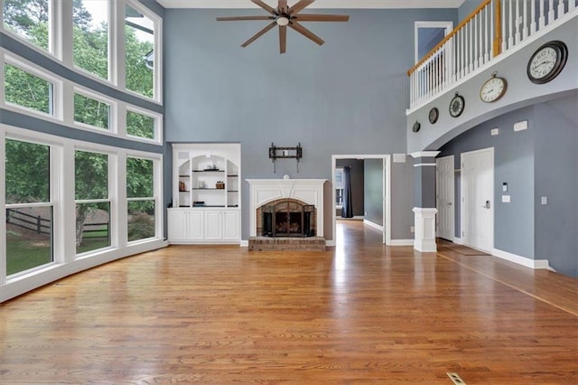 212 Thorncliff Way, Acworth, GA 30101 - unfurnished living room featuring a towering ceiling, a ceiling fan, a brick fireplace, and light wood finished floors