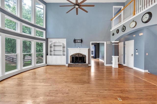 212 Thorncliff Way, Acworth, GA 30101 - unfurnished living room featuring a towering ceiling, a ceiling fan, healthy amount of natural light, light wood-style flooring, and a brick fireplace
