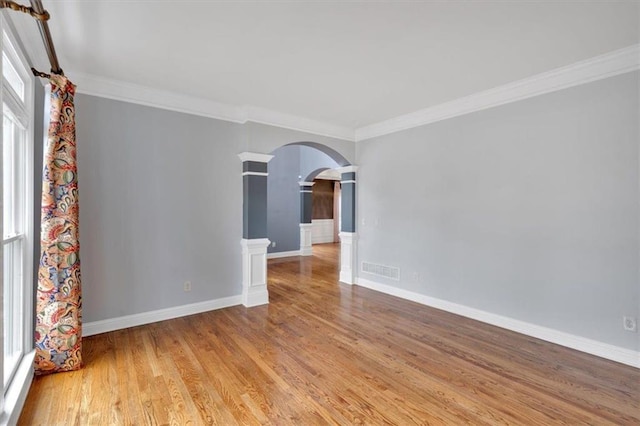212 Thorncliff Way, Acworth, GA 30101 - spare room featuring arched walkways, crown molding, light wood-style floors, and decorative columns