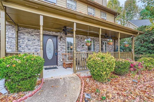 view of exterior entry with ceiling fan and a porch