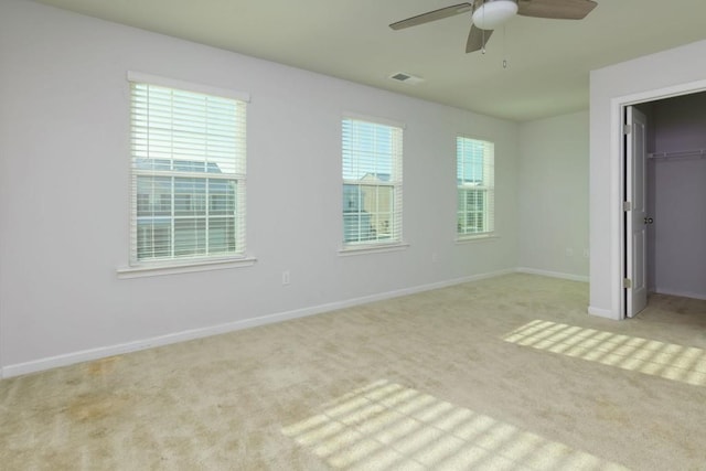 unfurnished bedroom featuring ceiling fan, a spacious closet, a closet, and light carpet