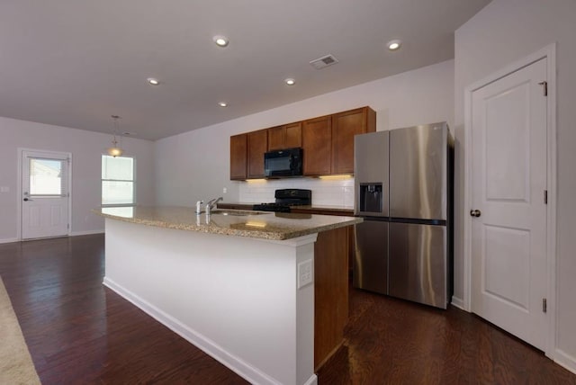 kitchen with a center island with sink, black appliances, pendant lighting, dark hardwood / wood-style flooring, and sink