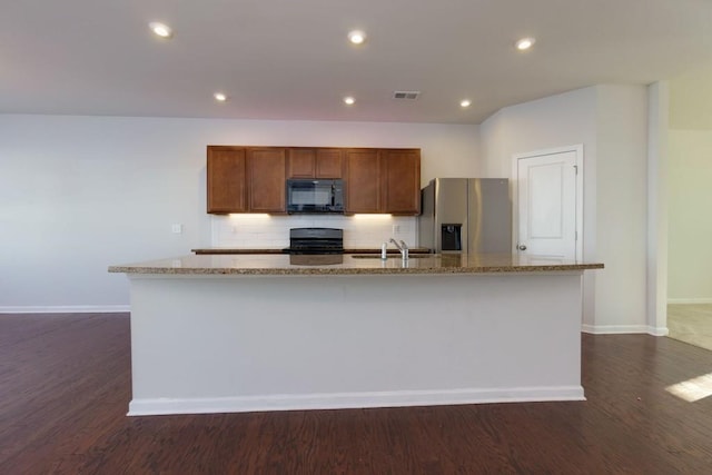 kitchen featuring stainless steel refrigerator with ice dispenser, decorative backsplash, stove, and an island with sink