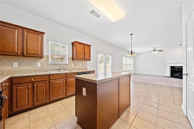 kitchen with light tile patterned floors, decorative backsplash, brown cabinetry, a kitchen island, and a fireplace