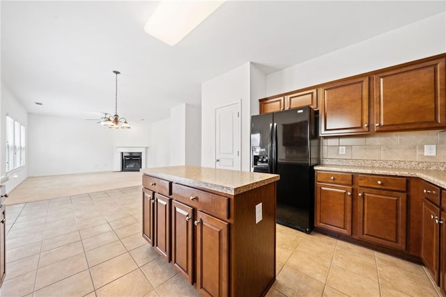 kitchen featuring light tile patterned floors, tasteful backsplash, a kitchen island, black refrigerator with ice dispenser, and a fireplace