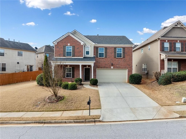 traditional-style home with a garage, concrete driveway, brick siding, and fence