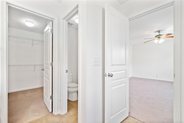 hall featuring light tile patterned floors, baseboards, and light colored carpet