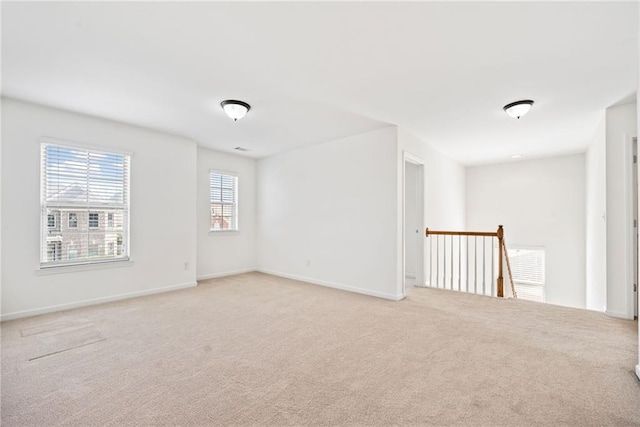 empty room featuring light colored carpet and baseboards
