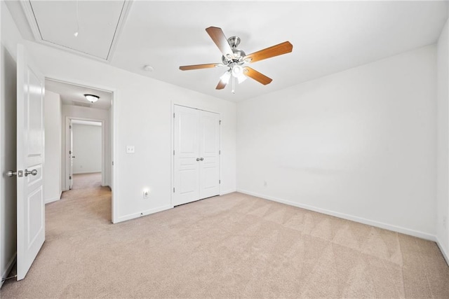unfurnished bedroom featuring light carpet, ceiling fan, attic access, and baseboards