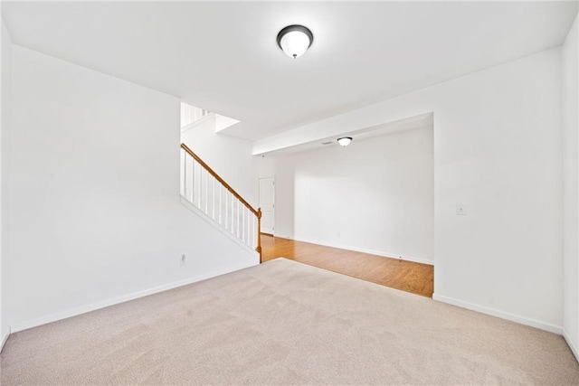 carpeted spare room with stairway and baseboards