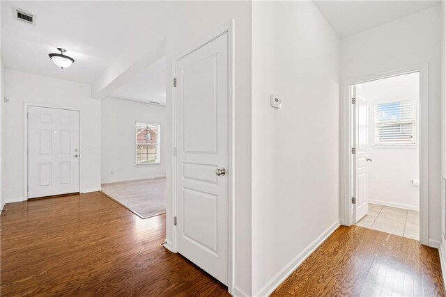 hallway with wood finished floors, visible vents, and baseboards