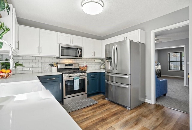 537 Autumn Ridge Dr, Canton, GA 30115 - kitchen featuring appliances with stainless steel finishes, blue cabinets, white cabinets, light countertops, and a textured ceiling