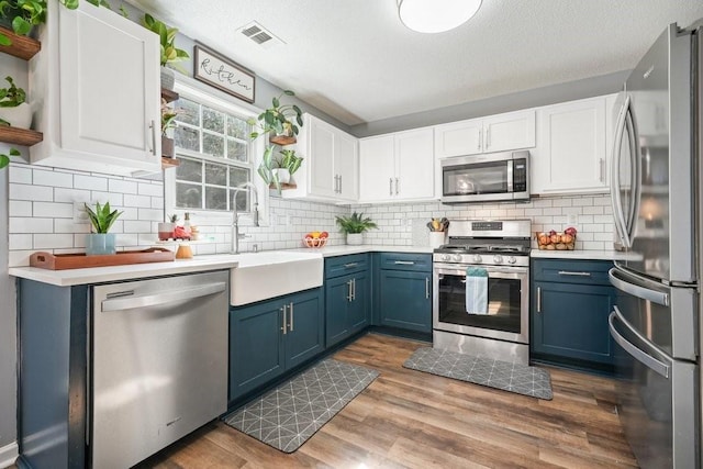 537 Autumn Ridge Dr, Canton, GA 30115 - kitchen with stainless steel appliances, blue cabinetry, a sink, white cabinets, and light countertops