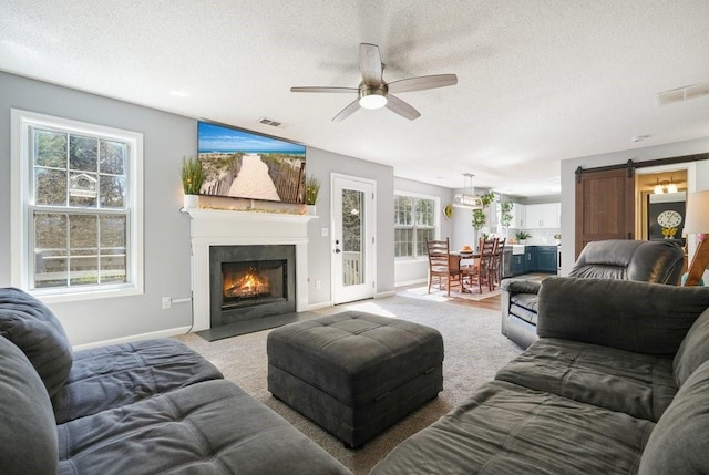 537 Autumn Ridge Dr, Canton, GA 30115 - living area with a ceiling fan, a barn door, a fireplace with flush hearth, baseboards, and a textured ceiling