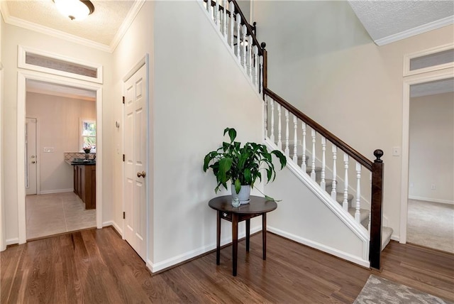 stairway with hardwood / wood-style flooring, ornamental molding, and a textured ceiling