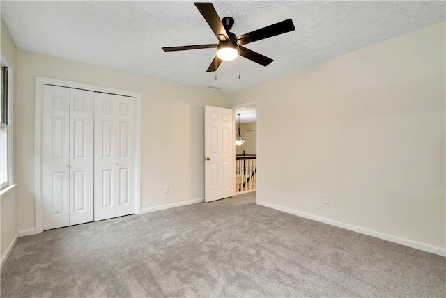 unfurnished bedroom featuring ceiling fan, carpet floors, a closet, and a textured ceiling