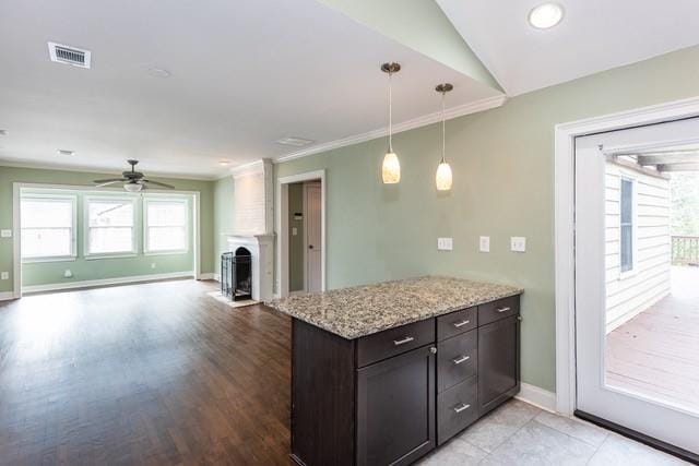 kitchen with visible vents, baseboards, open floor plan, ornamental molding, and hanging light fixtures