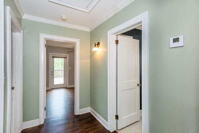 hall featuring dark wood-style floors, baseboards, and ornamental molding