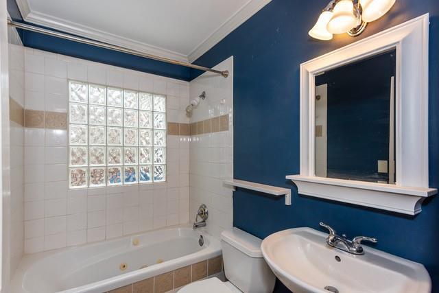 bathroom with crown molding, toilet,  shower combination, and a sink