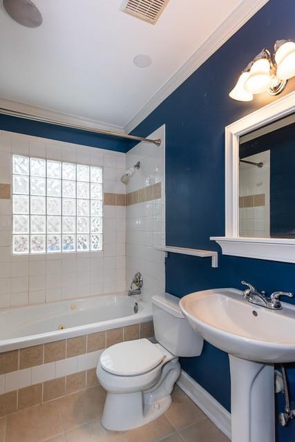 bathroom with visible vents, ornamental molding, tile patterned flooring, tiled shower / bath combo, and toilet