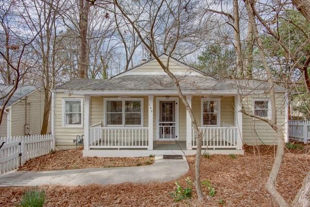 bungalow-style home featuring covered porch and fence