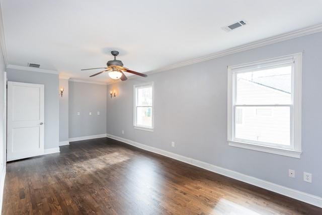 spare room featuring visible vents, dark wood-style flooring, baseboards, and ornamental molding