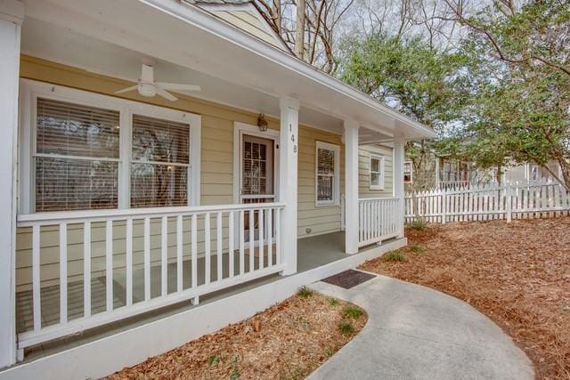 doorway to property with a ceiling fan, a porch, and fence