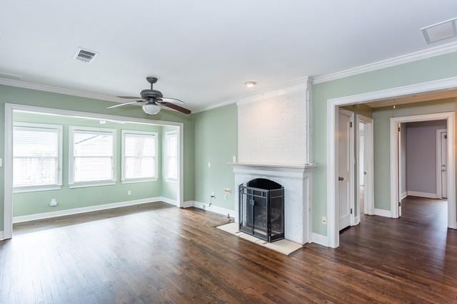 unfurnished living room featuring dark wood-type flooring, a fireplace with flush hearth, crown molding, and visible vents