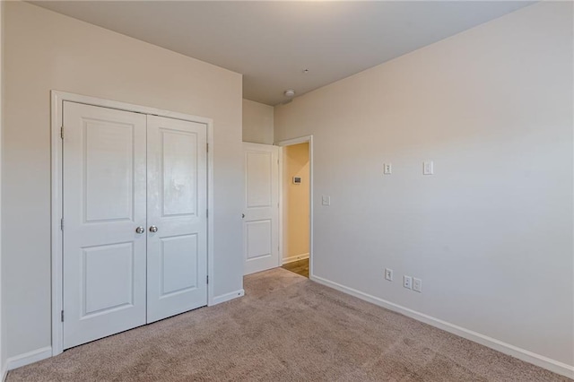 unfurnished bedroom with light carpet and a closet