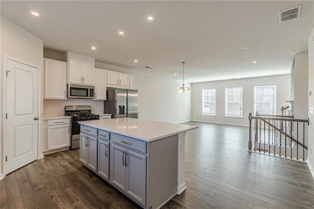 kitchen featuring white cabinets, a kitchen island, appliances with stainless steel finishes, and tasteful backsplash