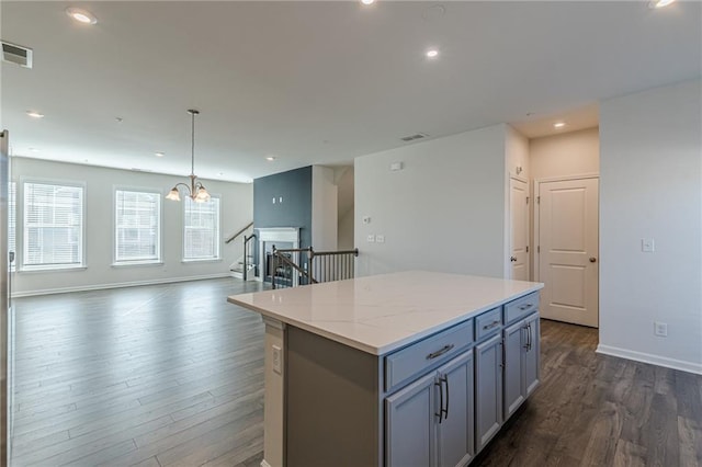 kitchen with dark hardwood / wood-style flooring, a notable chandelier, decorative light fixtures, gray cabinets, and a kitchen island