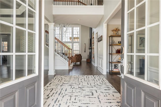 entrance foyer featuring dark wood-style floors, stairway, and decorative columns