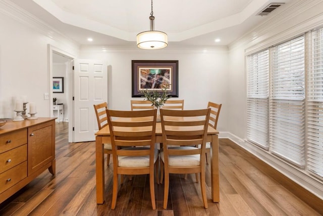 dining area with hardwood / wood-style floors, a tray ceiling, and ornamental molding