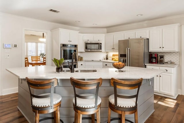 kitchen featuring white cabinetry, a kitchen island with sink, stainless steel appliances, and a breakfast bar