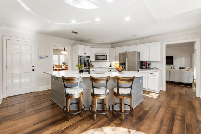 kitchen featuring white cabinetry, stainless steel appliances, and a center island with sink