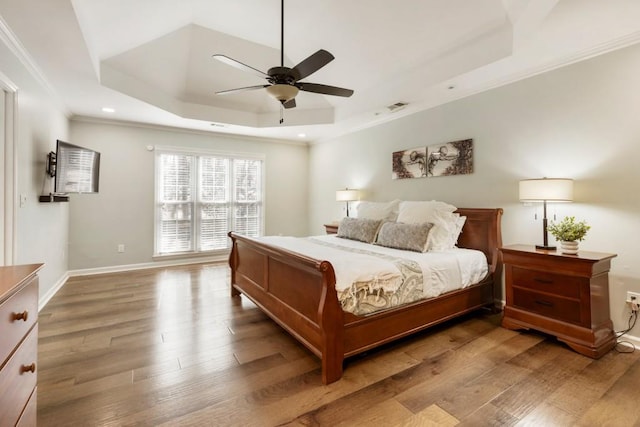 bedroom featuring a raised ceiling, wood-type flooring, and ornamental molding