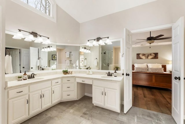 bathroom featuring ceiling fan, vanity, an enclosed shower, and a towering ceiling