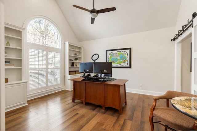 office featuring hardwood / wood-style floors, high vaulted ceiling, a barn door, and ceiling fan